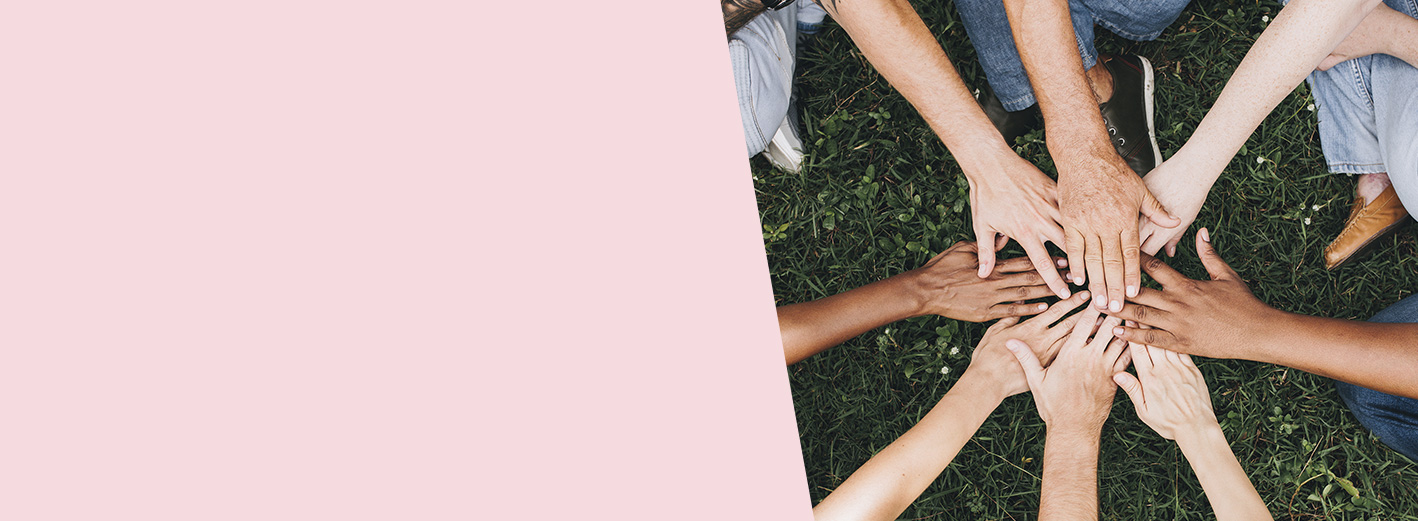 Hands of diverse skin tones join together as a symbol of teamwork.